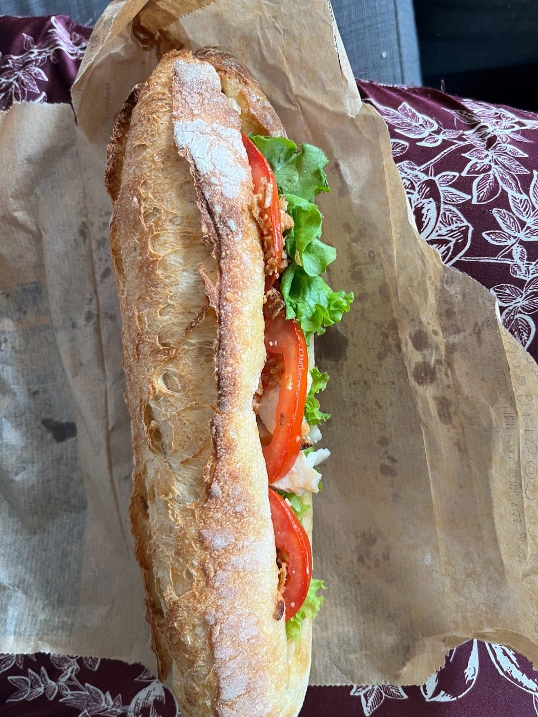Un sandwich garni sur pain de tradition fariné, salade et tomate, dans son papier.