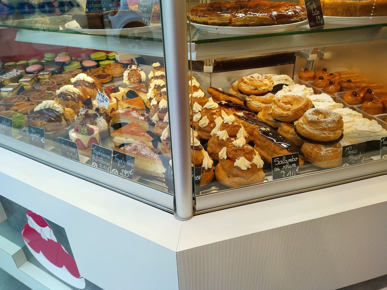 La vitrine réfrigérée de pâtisseries : macarons, entremets, choux et tartes sur deux niveaux.